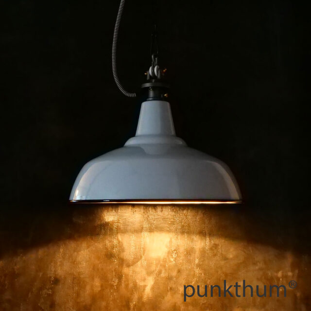 Hellgraue Emaillelampe, Industrielampe mit Stahlguss-Aufhängung und Textilkabel, eingeschaltet.