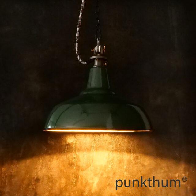 Dunkelgrüne Emaillelampe, Industrielampe mit Stahlguss-Aufhängung und Textilkabel, eingeschaltet.