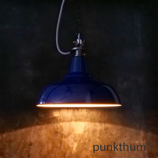 Dunkelblaue Emaillelampe, Industrielampe mit Stahlguss-Aufhängung und Textilkabel, eingeschaltet.