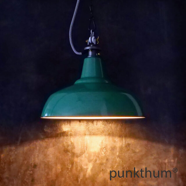 Grüne Emaillelampe, Industrielampe mit Stahlguss-Aufhängung und Textilkabel, eingeschaltet.