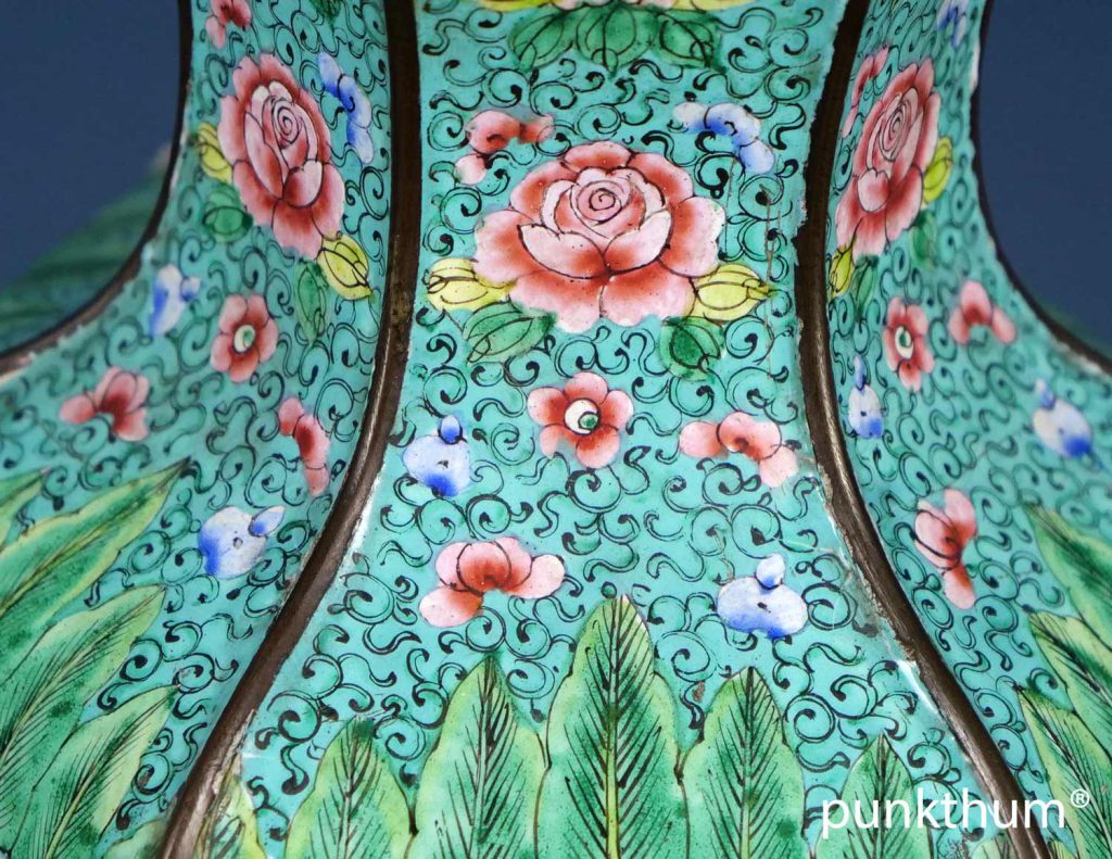 Der Grund ist türkisgrün, mit pflanzlichen Ornamenten, Blumen in rose und hellblau und Palmetten.